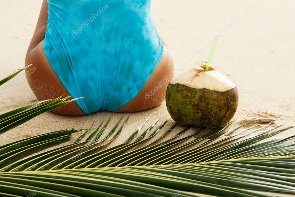 Female back and coconut drink on the beach