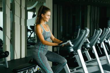 spor salonunda sabit bisiklet üzerinde sportif genç kadın
