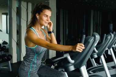 spor salonunda sabit bisiklet üzerinde sportif genç kadın