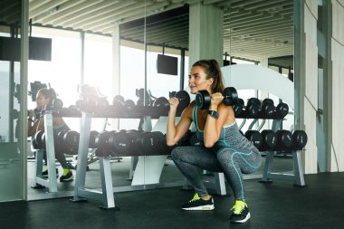Spor salonunda dumbbells ile çalışan genç güzel kadın