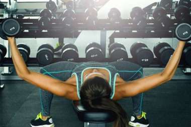 Spor salonunda dumbbells ile çalışan genç güzel kadın