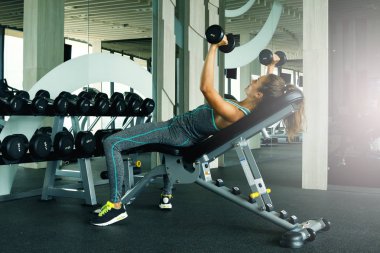 Spor salonunda dumbbells ile çalışan genç güzel kadın