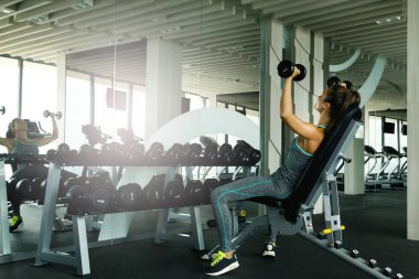 Spor salonunda dumbbells ile çalışan genç güzel kadın