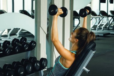 Spor salonunda dumbbells ile çalışan genç güzel kadın