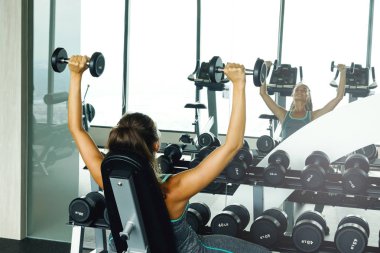 Spor salonunda dumbbells ile çalışan genç güzel kadın