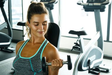 Spor salonunda dumbbells ile çalışan genç güzel kadın