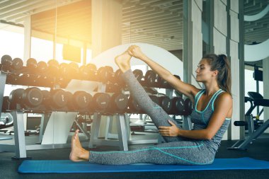 Spor salonunda germe egzersiz yaparak sportif genç kadın