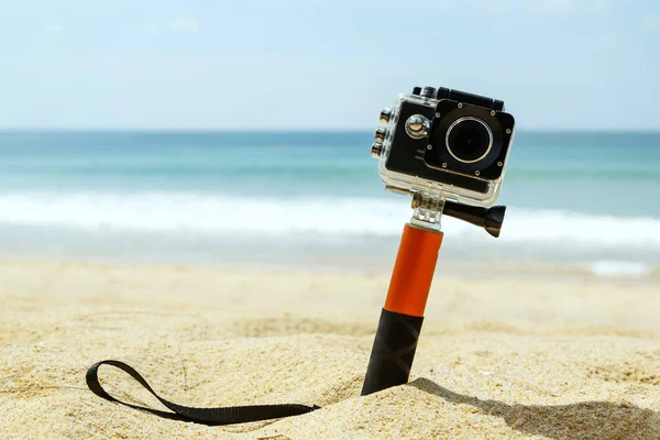 Action camera in waterproof case with monopod on the beach