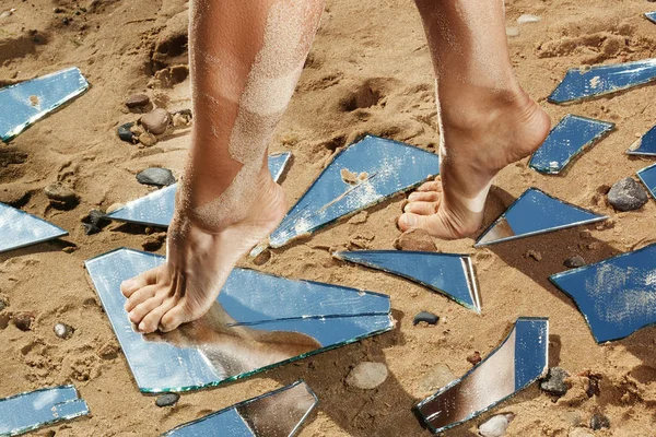 Kadın bacakları ve ayna kırıkları kum üzerinde