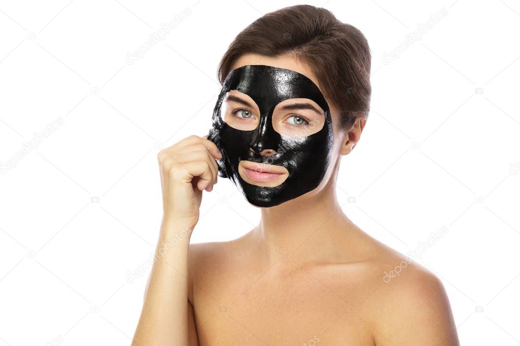 Woman with purifying black mask on her face isolated on white background