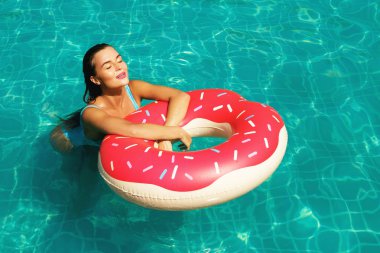 Güzel genç kadın ve şişme halka şeklinde çörek havuzda yüzmek