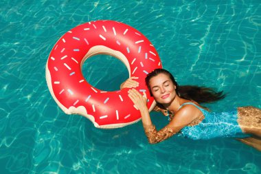 Güzel genç kadın ve şişme halka şeklinde çörek havuzda yüzmek