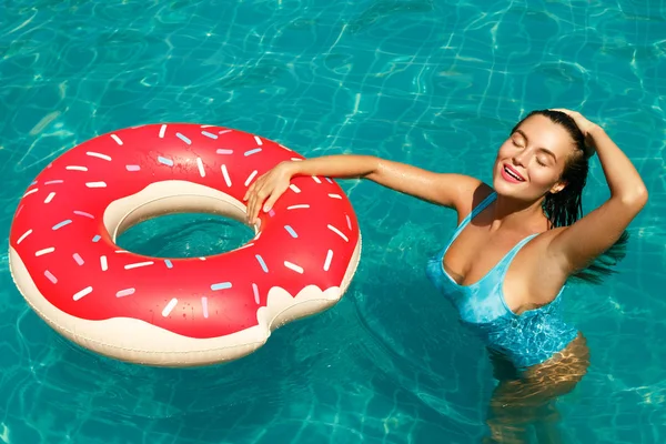 美丽的年轻女子和充气游泳圈的形状甜甜圈在池中 — 图库照片
