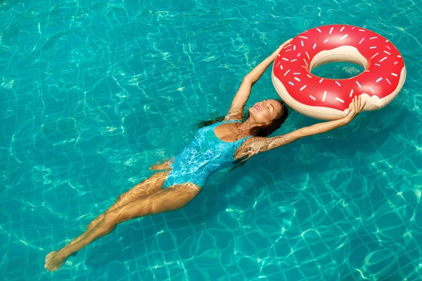 美丽的年轻女子和充气游泳圈的形状甜甜圈在池中 — 图库照片