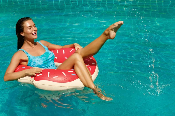 Happy woman and inflatable swim ring in shape of a donut in the pool
