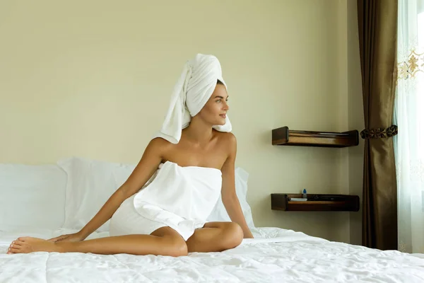 Woman with towel on her head is relaxing in bedroom after shower