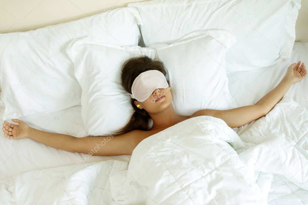 Woman is wearing eye mask and using earplugs for better sleeping