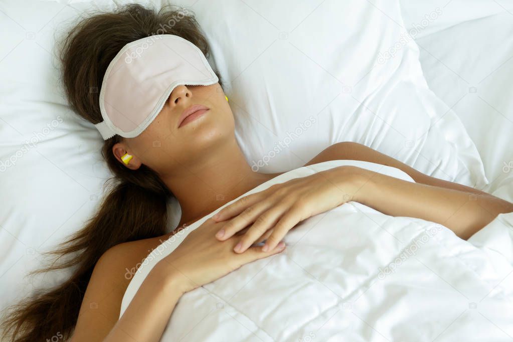 Woman is wearing eye mask and using earplugs for better sleeping