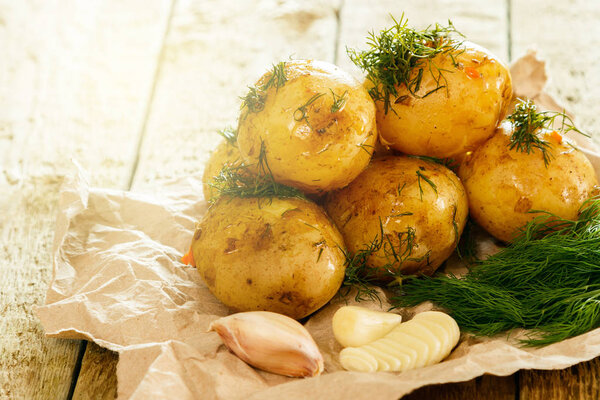 Baked potatoes with dill and garlic on wooden table