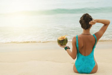 Kumsalda hindistan cevizli mutlu kadın.