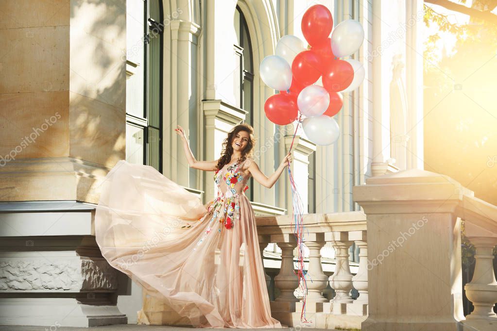 Lovely woman in beautiful dress with colorful balloons