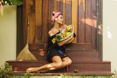 Sepet egzotik meyve dolu güzel bir kadınla kapının eşiğine evinin oturuyor