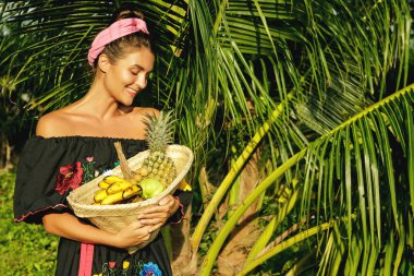 Sepet tropikal bahçe içinde egzotik meyve dolu olan mutlu kadın