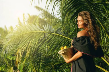 Sepet tropikal bahçe içinde egzotik meyve dolu olan mutlu kadın