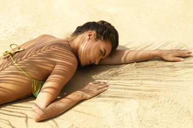 Sıcak yaz günü. Güzel kadın beach palm yaprak altında yatan