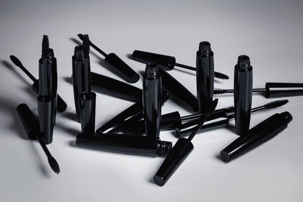 Mascara brushes and containers on white background