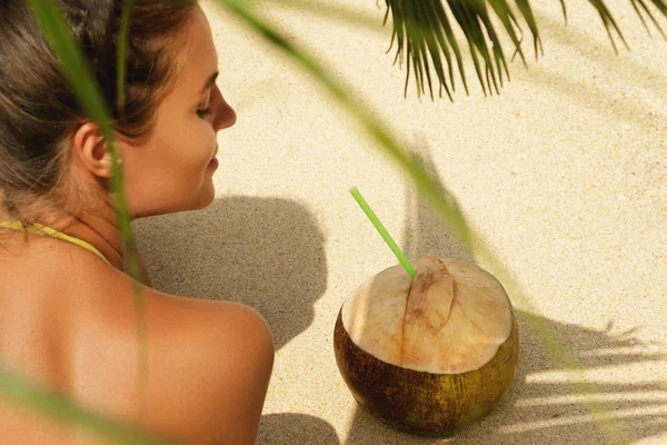 沙滩上棕榈叶下的椰子饮料妇女 — 图库照片