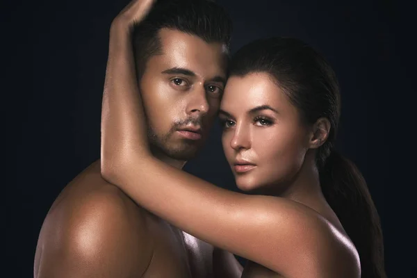 Portrait of young beautiful couple in studio on black background