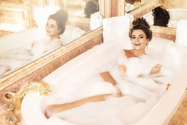 美丽的年轻妇女洗澡与泡沫在豪华公寓 — 图库照片