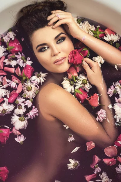 Beautiful woman in bath with flowers. Rejuvenation and relaxation concept