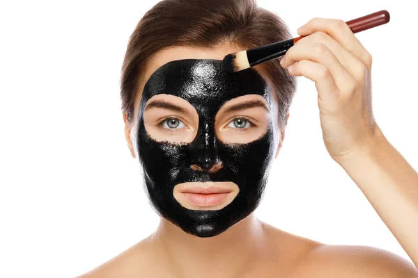 Beautiful Woman Applying Purifying Black Mask Her Face White Background — Stock Photo, Image