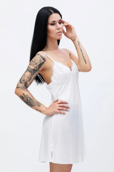 Woman with tattoos wearing beautiful nightgown