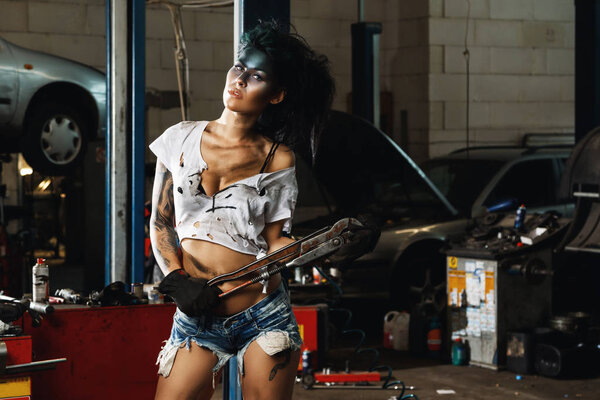 Woman mechanic in the garage with artistic makeup on her face stylized like a dirty spot