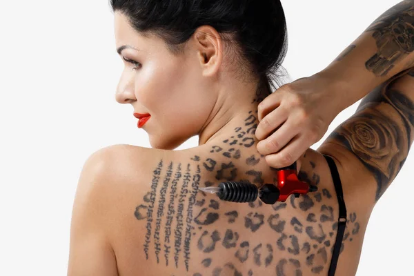 Young woman tattooist with a tattoo-machine in her hand on white background