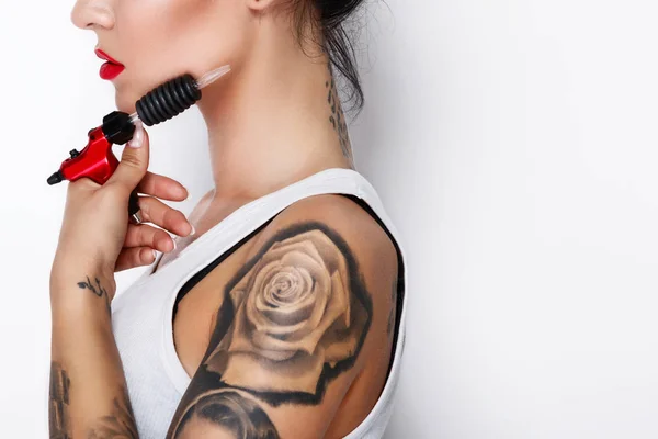 Young woman tattooist with a tattoo-machine in her hand on white background