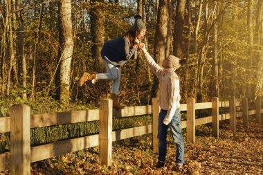 Sıcak kazak ve yünlü şapkalar güneşli sonbahar günü parkta giyen genç çift