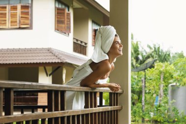 Vacations in tropical warm country. Happy and beautiful woman on the balcony after shower. clipart