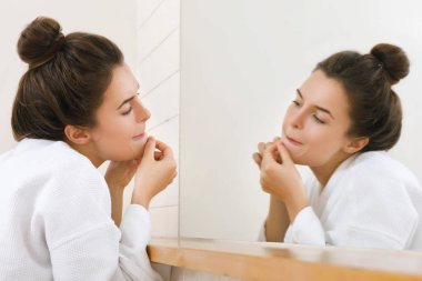 Woman squeeze pimples in the bathroom  clipart