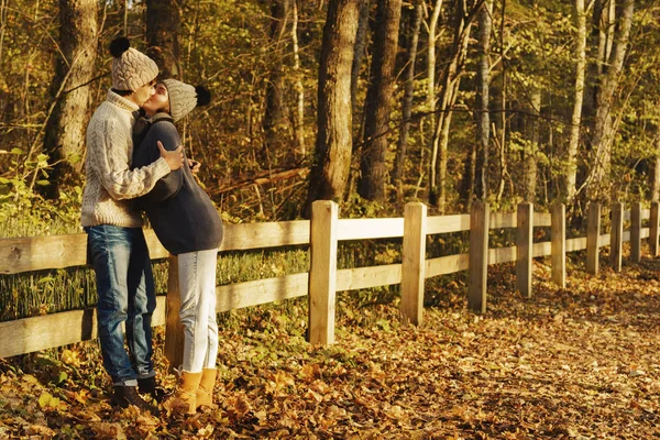 Sıcak kazak ve yünlü şapkalar güneşli sonbahar günü parkta giyen genç çift