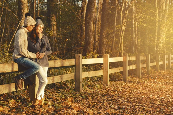 Sıcak kazak ve yünlü şapkalar güneşli sonbahar günü parkta giyen genç çift