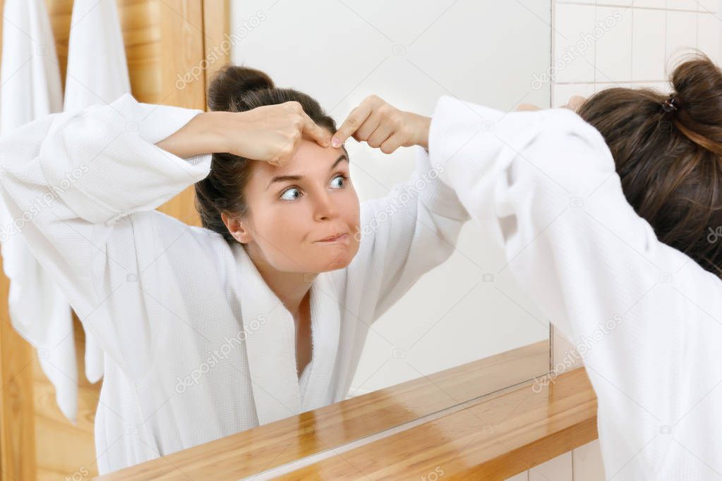 Woman squeeze pimples in the bathroom 
