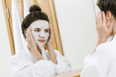 Kadın banyoda yüzünde sac maskesi uygulama