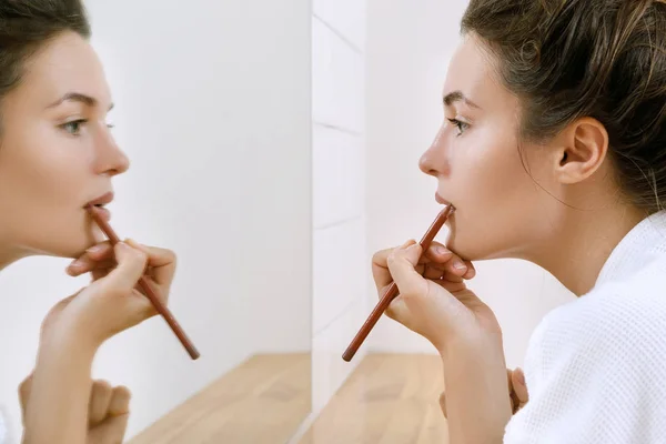 Woman drawing lip contour with a pencil