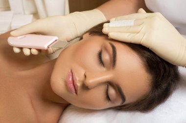 Ultrasonik yüz temizlik işlemi sırasında profesyonel güzellik spa salonda güzel kadın
