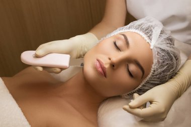 Ultrasonik yüz temizlik işlemi sırasında profesyonel güzellik spa salonda güzel kadın