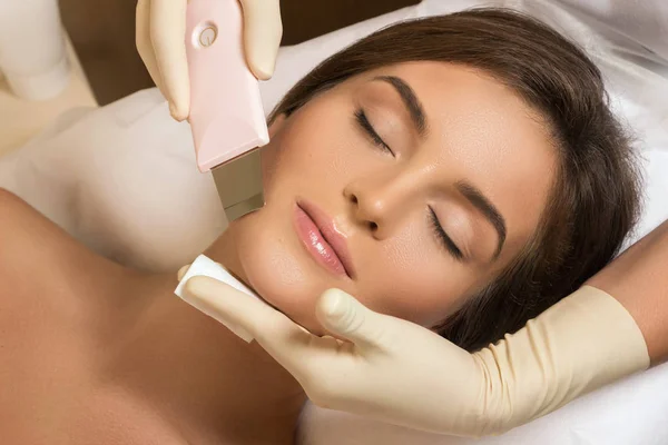 Beautiful woman in professional beauty spa salon during ultrasonic facial cleansing procedure